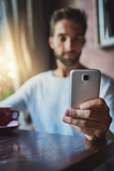 Poster - Man, phone and communication in coffee shop for social media, app and check menu on online website. Male person, mobile and text message in restaurant for contact, conversation and customer review