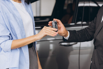 Wall Mural - Close-up shot of salesman or manager giving car keys to modern woman new car owner in car dealership