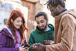 © Lomb - Diverse friends using smartphone outdoors, multicultural group sharing digital content, inclusive social interaction