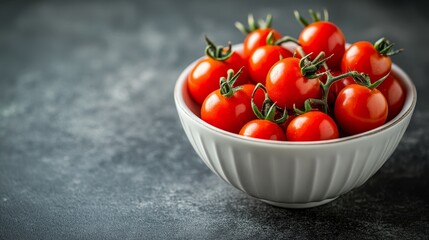 A bowl filled with bright red cherry tomatoes rests on a dark gray surface, creating a vibrant contrast. The tomatoes, fresh and plump, invite you to savor their sweet and juicy flavor.