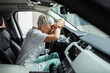 © Davor - Senior nurse exhausted and stressed in car holding coffee cup
