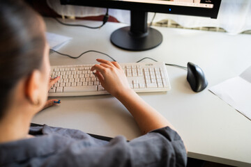 A young woman is sitting at a computer in the office