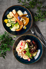 Wall Mural - Fried octopus with noodles, avocado and sauce with grilled salmon fillet with cucumbers, oranges, parsley and sauce.