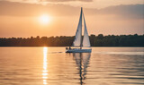 A sailboat sails across a calm lake at sunset