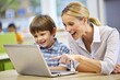 © hobonski - Teacher and Student Learning with Laptop in Classroom.   A heartwarming scene of educational guidance unfolds as an adult and child engage with a laptop together.