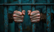 © Stock Images - Hands gripping rusty prison bars in a dim cell