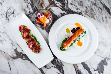 Wall Mural - Salmon fillet with spinach and sauces and cold appetizer carpaccio with tuna, avocado, algae, strawberries, spinach, sesame seeds and sauce.