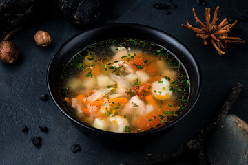 Sticker - Chicken broth with potatoes, onions, tomatoes, carrots and herbs in a dark plate.