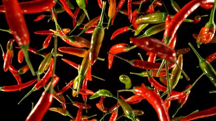 Poster - hot red and green chilli peppers flying on black background.