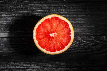 Wall Mural - sliced grapefruit on black wood background top view