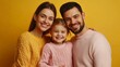 © fotofabrika - A cheerful family poses together with bright smiles against a vibrant yellow backdrop, showcasing their cozy sweaters during a joyful indoor moment