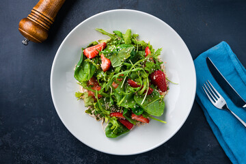 Canvas Print - Green salad with strawberries, spinach, arugula, spices, sauce and sesame seeds.