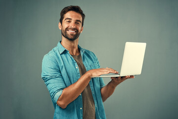 Fototapete - Laptop, happy and portrait of man in studio with research for creative software with project development. Smile, technology and graphic designer work on multimedia art on computer by gray background.