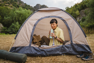 mature japanese woman sit in a tent and enjoy, rest on a camping trip