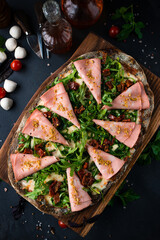 Poster - Pinza or pizza with ham, cheese, sun-dried tomatoes and arugula on rye dough.