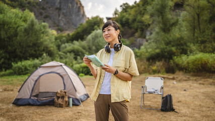 Front view of mature japanese woman stand and hold map look for road