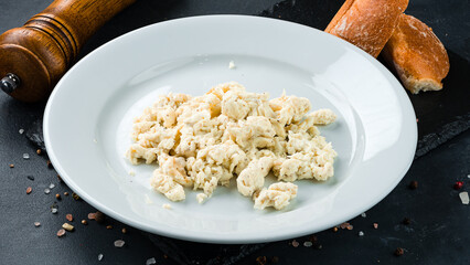 Canvas Print - Scrambled egg omelet with bread, salt and pepper on a dark background.