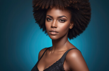 A young woman with dark skin and an afro hairstyle poses in front of a teal backdrop