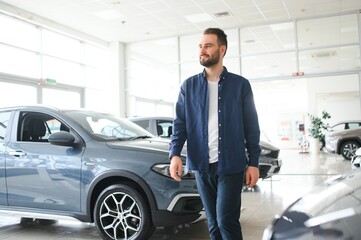 Wall Mural - Handsome bearded buyer in casual wear in dealership, guy standing near car