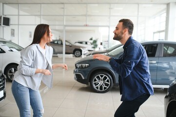 Wall Mural - The successful visit to the dealership. Happy young couple chooses and buying a new car for the family