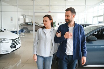 Wall Mural - It is the one car I want. Beautiful young couple standing at the dealership choosing the car to buy