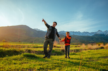 Poster - Father and son walking through picturesque mountain valley at sunset, father pointing in the distance