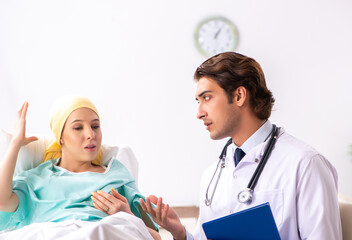 Wall Mural - Young handsome doctor visiting female oncology patient