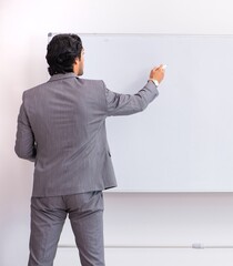 Wall Mural - Young handsome businessman standing in front of whiteboard