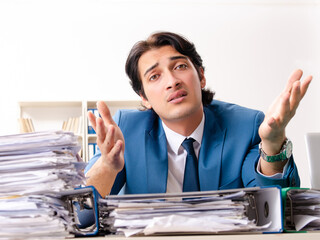 Wall Mural - Young handsome busy employee sitting in office