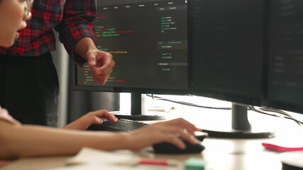 Back end or software developer manager supervising his team on new application program development on debugging and solving complex code algorithms on monitor. Burgeoning