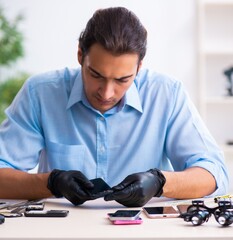 Wall Mural - Young male technician repairing mobile phone