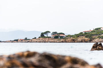 From the sandy shores of Di Bados, the rugged Sardinian coastline unfolds, where elegant villas nestle among the rocks and greenery. 