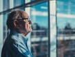 © Sahir_Stock - Older caucasian man gazing out of a large office window reflecting on something in bright natural light
