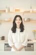 © sujeong - Smiling Young Woman Wearing Apron in a Bright Modern Kitchen