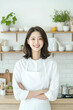 © sujeong - Smiling Young Woman Wearing Apron in a Bright Modern Kitchen