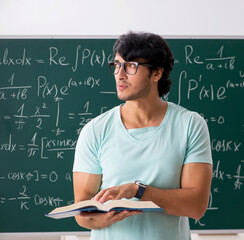 Canvas Print - Young male student mathematician in front of chalkboard