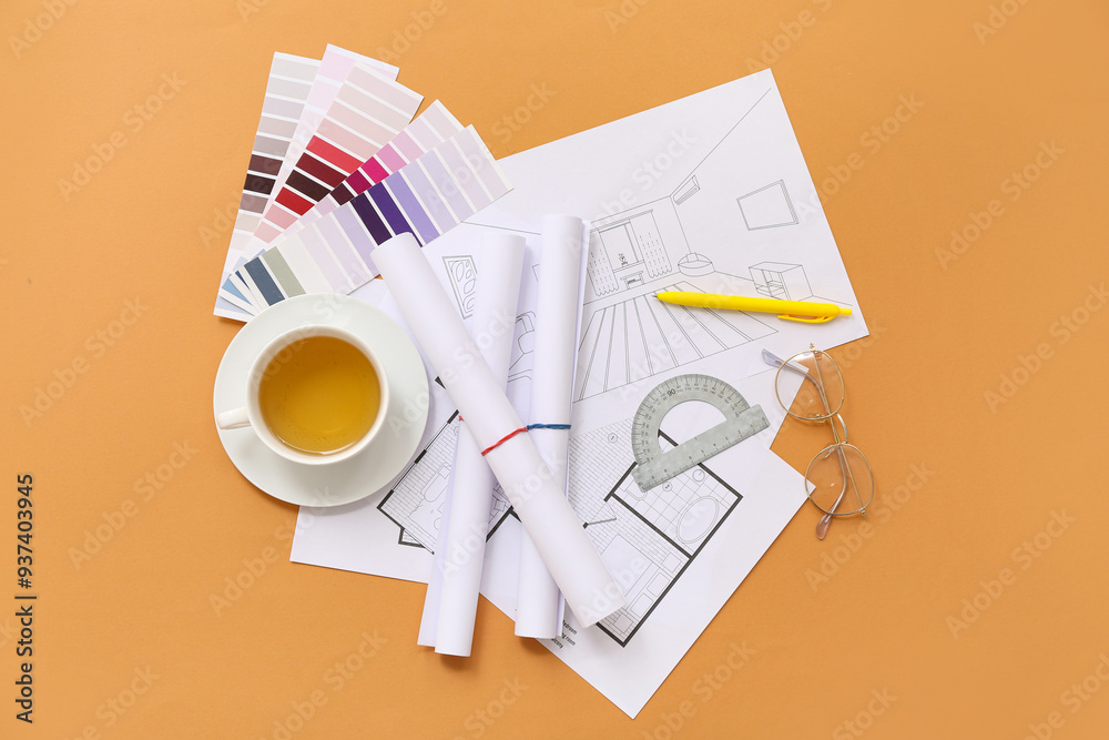 Architect's supplies with house plans and tea cup on orange background