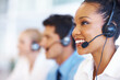 © peopleimages.com - Woman, talking and smile in call center for customer service, telemarketing and FAQ in office. Female agent, contact or headset at help desk with team, communication or bilingual consultant with tech