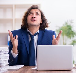 Wall Mural - Young male employee unhappy with excessive work