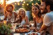 © btiger - Group Of Friends Dining Outdoors Warm Lighting Greenery Smiling Faces Summer Evening