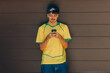 © carballo - young man or teenager in summer on the street with mobile phone and yellow t-shirt
