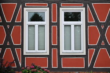 Exterior wall of a half-timbered house with two white windows