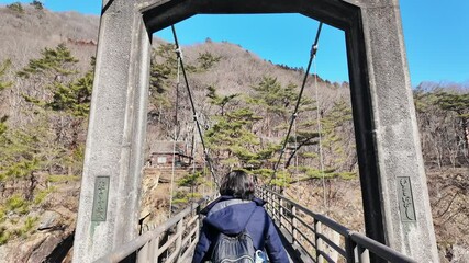 Fototapete - 吊り橋を渡る女性の後ろ姿