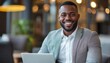 © Julia Jones - Smiling Young African American Businessman with Laptop at Cafe