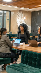 Gathered around a stylish table, three women share ideas and laughter while collaborating on a project in a chic office space, radiating positivity and teamwork