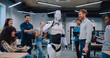 © ihorvsn - Diverse people gathering together to watch humanoid robot perform simple tasks. Asking questions and discussing results. Noting everything down on notepad. Man communicating with cyborg.