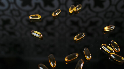 Bunch of yellow capsules pills scattered on a black surface Vitamin D3 production. Concept of taking vitamins, fish oil, bio supplements for health