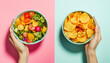 © StellaPattaya - One hand holding bowl of vegetable salad, other holding chips. Healthy natural organic fresh vegetarian food vs unhealthy processed fast junk food. Lunch or snack decision