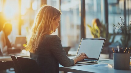 Poster - blonde casual businesswoman using a laptop during a meeting, showcasing modern work culture