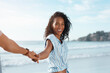 © peopleimages.com - Portrait, pov and happy woman holding hands at beach for summer travel, vacation and laughing at funny joke. Face, smile and lead couple to sea for holiday, relax or follow partner for love on island
